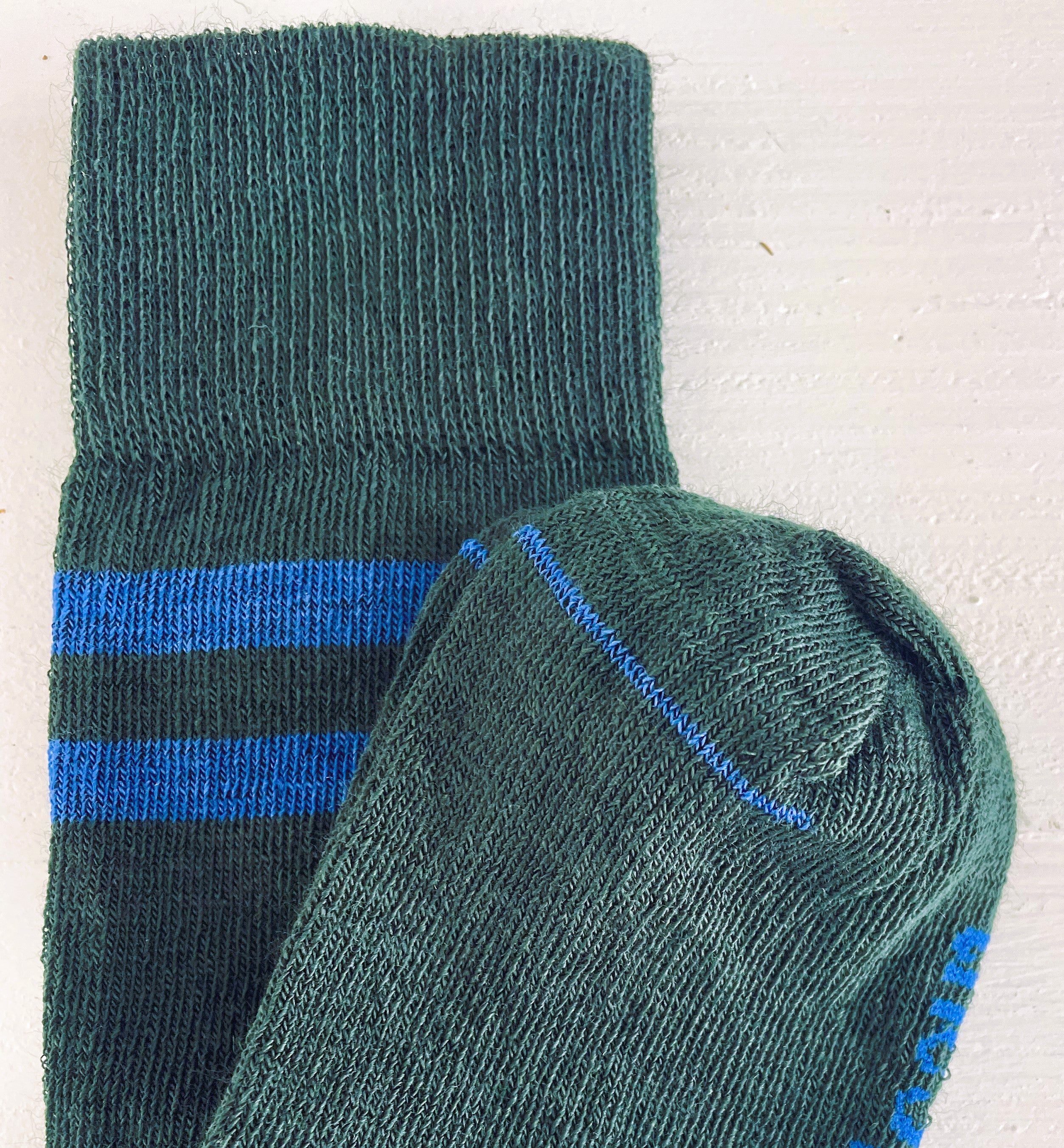 close up of dark green coloured merino socks with 2 bold blue stripes. warm and sporty